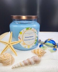 A 16 oz Apothecary Jar Candle - Lavender is displayed on a white towel, surrounded by seashells, a starfish, and a decorative blue crab.