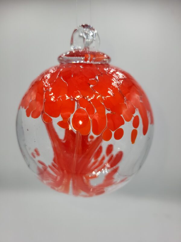 Red and clear glass ornament with abstract design.
