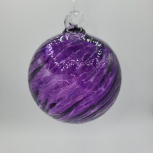A round glass ornament with swirling purple and black patterns hangs against a plain white background.