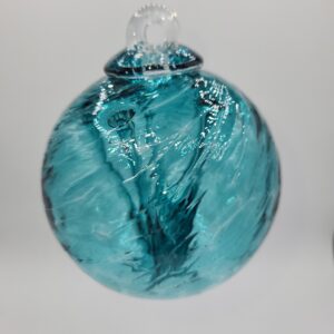 A blue and clear glass ornament with swirling patterns hangs against a plain white background.