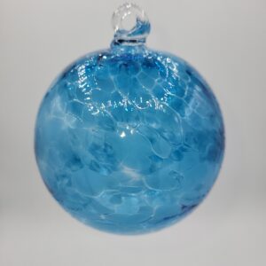A round, blue glass ornament with a textured, mottled pattern hangs against a plain white background. The ornament has a small clear glass loop at the top for hanging.