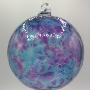 A round glass ornament with a mix of blue, purple, and pink swirled patterns, hanging against a plain white background.