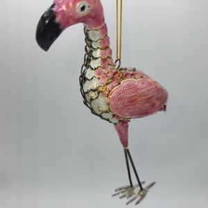 A decorative pink flamingo ornament with metallic golden and white scales, hanging by a thin gold string against a plain, light background.