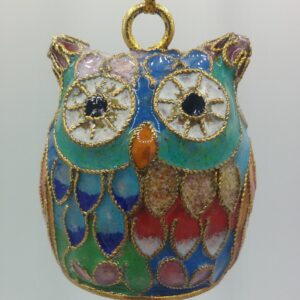 A colorful enamel and gold owl pendant with intricate designs, featuring large eyes, multi-colored feathers, and a gold hanging loop against a plain background.