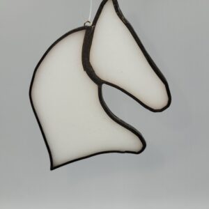 A stained glass ornament shaped like a horses head, outlined in black with white glass, hanging by a thin string against a plain background.