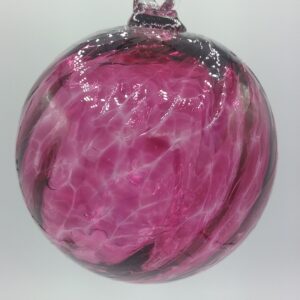 A glass ornament with swirls of pink and dark red, featuring a glossy, marbled texture and a clear loop at the top for hanging, displayed against a plain white background.