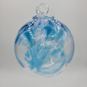 A round, clear glass ornament with swirling blue patterns hangs against a plain white background.