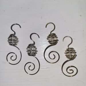 Four decorative wire ornament hooks, two silver and two gold, each with a spiral design and a clear bead encased in wire, are displayed on a white surface.