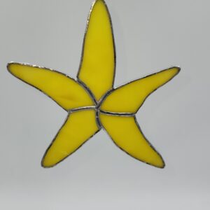 A yellow stained glass ornament shaped like a starfish, outlined with silver metal, is hanging against a plain, light background.