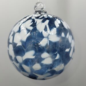 A round, glass ornament with a mix of white and blue petal-like patterns, hanging against a plain light gray background.