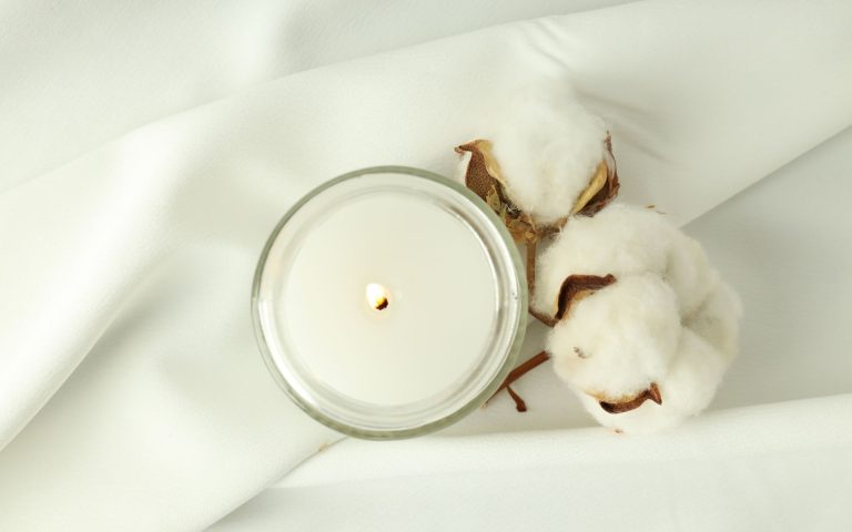 A clean burning soy candle next to a sprig of cotton